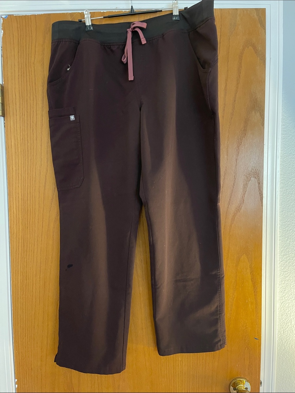 FIGS Technical Collection Scrub Pants in Deep Plum with Pink Accent.